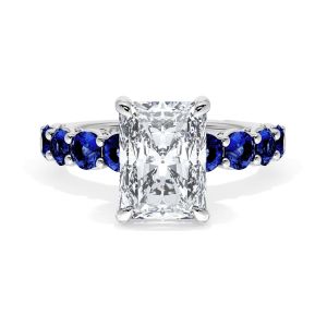 415RAD95X7BS Platinum top view, radiant cut center stone on a white metal band lined with round blue sapphires