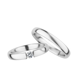 Christian Bauer 240999 14 karat white gold diamond wedding band, angled view of a brushed flat face with a round stone held in tension between squared polished ends, shown with its matching ring