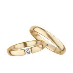 Christian Bauer 240999 14 karat yellow gold diamond wedding band, angled view of a brushed flat face with a round stone held in tension between squared polished ends, shown with its matching ring