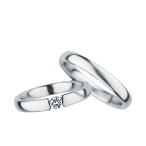 Christian Bauer 240999 platinum diamond wedding band, angled view of a brushed flat face with a round stone held in tension between squared polished ends, shown with its matching ring