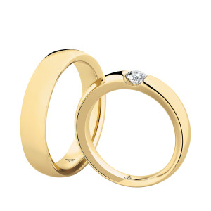 Christian Bauer 241600 18 karat yellow gold diamond wedding band, angled view of a polished flat face with square edges and a round stone tension set in a diagonal slot, shown with its matching ring