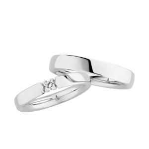 Christian Bauer 241689 18 karat white gold diamond wedding band, angled view of a polished flat face whose open ends hold one round stone in four small prongs, shown with its matching ring