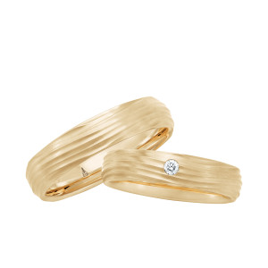 Christian Bauer 241732 14 karat yellow gold diamond wedding band, angled view of a matte surface cut with irregular wave grooves and one round stone flush set on top, shown with its matching ring