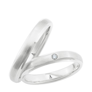 Christian Bauer 241737 18 karat white gold diamond wedding band, angled view of a brushed satin center between narrow polished beveled edges with one small flush set stone, shown with its matching ring