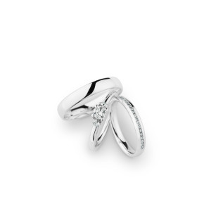 Christian Bauer 246965 platinum diamond wedding band, angled view of a polished rounded profile with a channel set row of tiny stones along one edge halfway around, shown with its matching rings