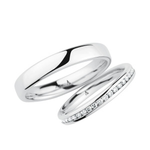 Christian Bauer 246975 18 karat white gold diamond wedding band, angled view of a polished rounded profile with a full channel set row of small stones offset toward one edge, shown with its matching ring