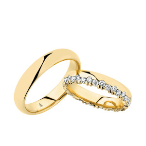 Christian Bauer 247023 18 karat yellow gold diamond wedding band, angled view of a polished rounded profile with a full row of round stones in scalloped prongs on one edge, shown with its matching ring