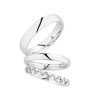 Christian Bauer 247073 14 karat white gold diamond wedding band, angled view of a rounded profile with two staggered rows of round stones in shared prongs across the front half, shown with its matching rings