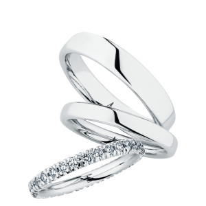 Christian Bauer 247100 platinum diamond wedding band, angled view of a rounded profile with round stones in shared prongs running around the full circumference, shown with its matching rings