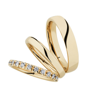 Christian Bauer 247106 14 karat yellow gold diamond wedding band, angled view of a rounded profile with evenly spaced round stones in shared prongs around the whole circumference, shown with its matching rings