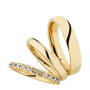 Christian Bauer 247106 18 karat yellow gold diamond wedding band, angled view of a rounded profile with evenly spaced round stones in shared prongs around the whole circumference, shown with its matching rings