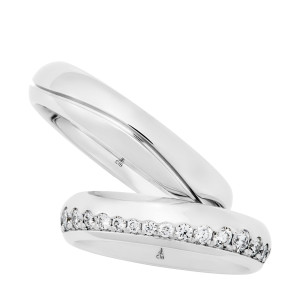 Christian Bauer 247143 14 karat white gold diamond wedding band, angled view of a polished dome with a continuous row of round stones set in a channel along one edge, shown with its matching ring