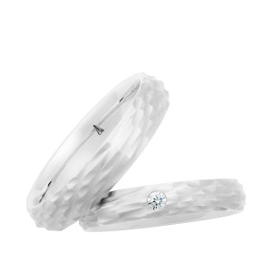 Christian Bauer 274788 14 karat white gold wedding band, angled view of a matte hammered surface of chisel cut facets covering the whole face and its irregular faceted edges, shown with its matching ring