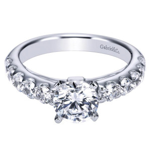 Gabriel & Co. ER4246W44JJ 14 karat white gold Contemporary engagement ring, angled view of the round center beside large shared prong rounds on a broad flat shank