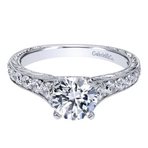 Gabriel & Co. ER10119W44JJ 14 karat white gold Victorian engagement ring, angled view of the round center over graduated side stones with engraved scrollwork along the outer rim