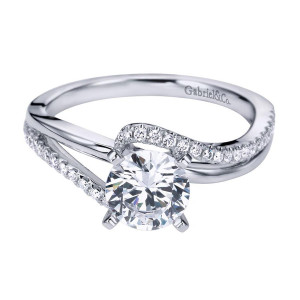 Gabriel & Co. ER6974W44JJ 14 karat white gold Contemporary engagement ring, angled view of a round center where a pave rail crosses over a plain polished rail