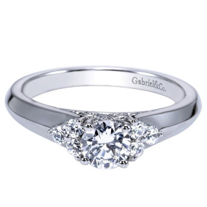 Gabriel & Co. ER98543W44JJ 14 karat white gold Contemporary engagement ring, angled view of the round center flanked by small stone clusters above a broad flat shank