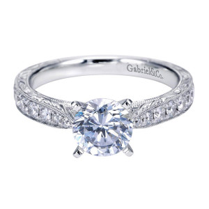 Gabriel & Co. ER7529W44JJ 14 karat white gold Victorian engagement ring, angled view of the round center beside a straight stone row above engraved leaf vines