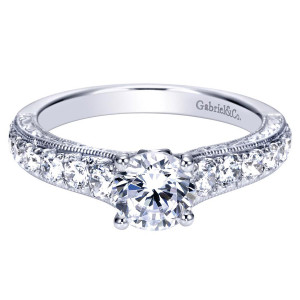 Gabriel & Co. ER98717W44JJ 14 karat white gold Contemporary engagement ring, angled view of the round center above graduated shoulder stones with milgrain edging the rail