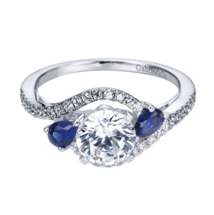 Gabriel & Co. ER5331PT3SA platinum Contemporary engagement ring, angled view of a round center flanked by blue pear stones above crossing pave curves