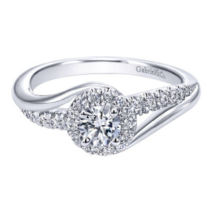 Gabriel & Co. ER910068W44JJ 14 karat white gold Contemporary engagement ring, front view of the round center in a single halo where one pave arm sweeps past