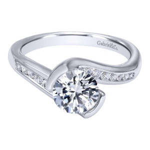 Gabriel & Co. ER10436W44JJ 14 karat white gold Contemporary engagement ring, angled view of the round center clasped by smooth curved arms above a channel set row