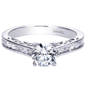 Gabriel & Co. ER7898W44JJ 14 karat white gold Contemporary engagement ring, front view of the round center raised above a channel row with scrollwork cut into the sides