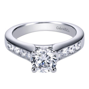 Gabriel & Co. ER3962W44JJ 14 karat white gold Contemporary engagement ring, front view of the round center flanked by channel set rounds in a wide flat shank