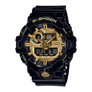 Casio G-Shock GA710GB-1A watch, front view of a glossy black case with a gold tone dial and a textured gold button below