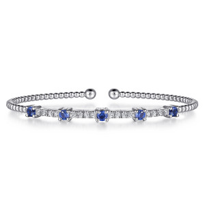Gabriel & Co. BG4706-57W45SA 14 karat white gold Bujukan bangle, front view of blue stones alternating with small diamonds in front of the ball-tipped opening
