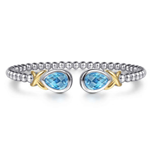 Gabriel & Co. BG5210-57MZJBT sterling silver and 14 karat yellow gold Bujukan bangle, front view of the beaded open cuff with a blue pear stone at each end of the gap