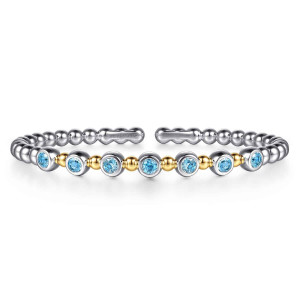 Gabriel & Co. BG5247-57MZJBT sterling silver and 14 karat yellow gold Bujukan bangle, front view of round blue stones in rims alternating with small beads, across from the open gap