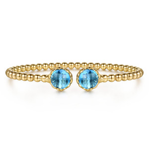 Gabriel & Co. BG5291E557Y4JBT 14 karat yellow gold Bujukan bangle, front view of the beaded cuff with a round blue stone facing the other across the gap