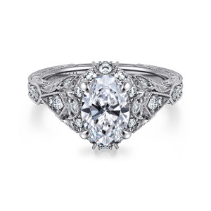 Gabriel & Co. ER12579O6W44JJ 14 karat white gold Victorian engagement ring, front view of an oval center inside a small diamond halo with pointed leaf panels on the shoulders