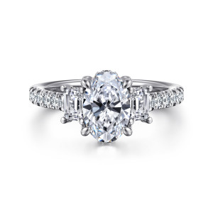 Gabriel & Co. ER14069O6W44JJ 14 karat white gold Contemporary engagement ring, front view of an oval center between step cut side stones, with diamonds along the shoulders
