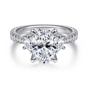 Gabriel & Co. ER15347O8W44JJ 14 karat white gold Classic engagement ring, front view of an oval center between half moon side stones with diamonds running down the band