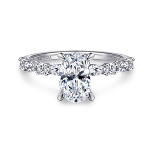Gabriel & Co. ER15607O6W44JJ 14 karat white gold Contemporary engagement ring, front view of an oval center on curved prongs above alternating round and elongated band diamonds