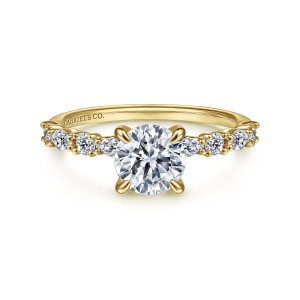 Gabriel & Co. ER15607R4Y44JJ 14 karat yellow gold Contemporary engagement ring, front view of the round center in teardrop claws flanked by elongated and round stones along the shoulders