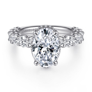 Gabriel & Co. ER15817O10W44JJ 14 karat white gold Classic engagement ring, front view of an oval center with a thin hidden halo edge and large round band stones