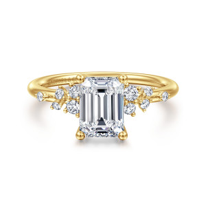 Gabriel & Co. ER15973E6Y44JJ 14 karat yellow gold Starlight engagement ring, front view of an emerald cut center with ball tipped prongs and scattered round diamonds on both shoulders