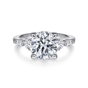 Gabriel & Co. ER16199R12W44JJ 14 karat white gold Contemporary engagement ring, front view of a round center with a round and an elongated diamond on each shoulder