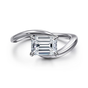 Gabriel & Co. ER16277E6W4JJJ 14 karat white gold Contemporary engagement ring, front view of an emerald cut center lying sideways between the crossing ends of the band