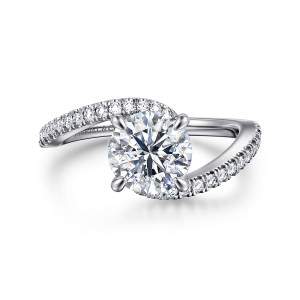 Gabriel & Co. ER16278R6W44JJ 14 karat white gold Contemporary engagement ring, top view of a round center in pointed prongs with a diamond lined band sweeping past