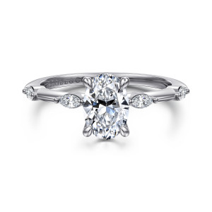 Gabriel & Co. ER16432O4W43JJ 14 karat white gold Starlight engagement ring, front view of an oval center between elongated stones set lengthwise on each shoulder