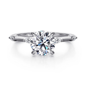 Gabriel & Co. ER16432R6W43JJ 14 karat white gold Starlight engagement ring, front view of a round center flanked by elongated diamonds set lengthwise along the thin band