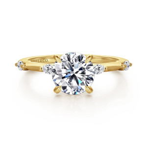 Gabriel & Co. ER16432R6Y43JJ 14 karat yellow gold Starlight engagement ring, front view of a round center flanked by narrow pointed diamonds set lengthwise on the shoulders
