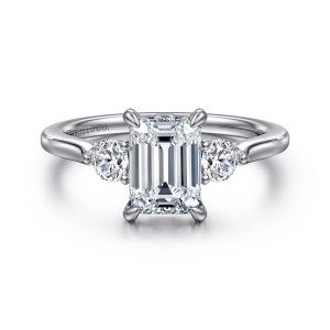 Gabriel & Co. ER16484E6W44JJ 14 karat white gold Lotus engagement ring, front view of an emerald cut center between two round side stones, held by slim claw prongs