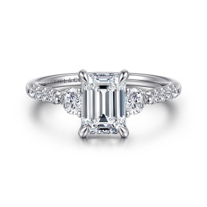 Gabriel & Co. ER16487E6W44JJ 14 karat white gold Lotus engagement ring, front view of an emerald cut center flanked by round diamonds, with small diamonds on the shoulders