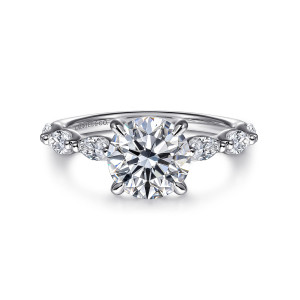 Gabriel & Co. ER16498R6W44JJ 14 karat white gold Contemporary engagement ring, front view of a round center flanked by elongated stones lying lengthwise on a slim band