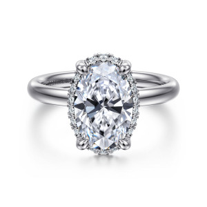 Gabriel & Co. ER16567O10W44JJ 14 karat white gold Contemporary engagement ring, front view of an oval center with halo diamonds peeking around its edge between rounded prongs
